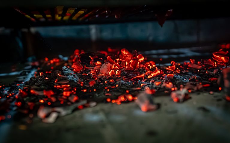 Close-up of glowing coals in a grill, highlighting the intense heat and vibrant colors.